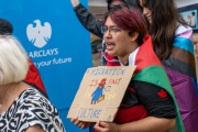 A young demonstrator holding a sign featuring Paddington Bear with the slogan MIGRATION IS PART OF OUR CULTURE participates in the Unity Demo Bournemouth held on 2026 10 03 along Commercial Road in Bournemouth, Dorset. The individual, draped in a flag, is captured advocating for the acceptance and positive role of migration while protesting in front of a Barclays branch.#jerryfennerphotography#newforestphotographer#bournemouth#unitydemobournemouth#migrationmatters#paddingtonbear