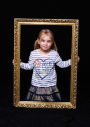 Young child posing with a picture frame in the photography studio