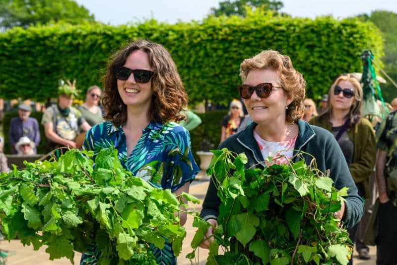 Two cheerful participants carry vibrant green foliage as they join in the festivities of the New Forest Green Man Parade 2026 at The Burley Manor in Burley, Hampshire, marking a lively celebration of local folklore and seasonal tradition.#jerryfennerphotography#newforestphotographer#greenmanparade#burleymanor#hampshireevents#folktraditions