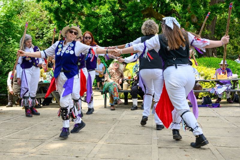 Members of a traditional Morris dancing troupe perform a lively stick dance outside The Queens Head in Burley, Hampshire, as part of the vibrant New Forest Green Man Parade 2026. Accompanied by a musician, the dancers demonstrate their heritage and commitment to local folklore during this community celebration.#jerryfennerphotography#newforestphotographer#morrisdancing#greenmanparade#burleyhampshire#traditionalculture