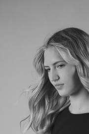 A contemplative portrait in monochrome, featuring soft, cascading waves and a minimalist black silhouette. The downward gaze creates an atmosphere of quietude, emphasised by gentle studio lighting that highlights natural textures and refined, understated styling.#jerryfennerphotography #monochromeportrait #studiophotography #portraiture #blackandwhite #quietmoments #minimaliststyle #softlighting #fineartportrait #contemplative